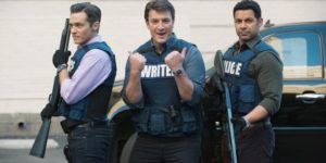 Three men in police vests pose together, two holding long guns.