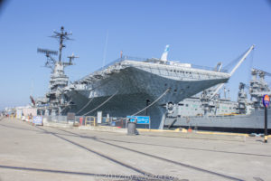 A large aircraft carrier docked at a pier under a clear sky.