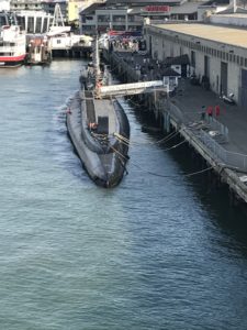 A submarine moored alongside a pier, viewed from above the water.