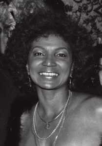 A black-and-white portrait of Nichelle Nichols smiling toward the camera.